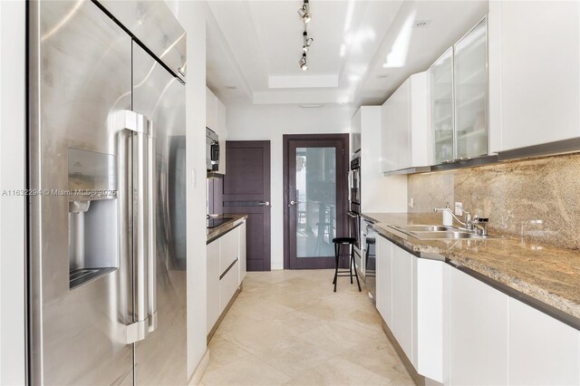 kitchen with white cabinets, stainless steel appliances, and a tray ceiling