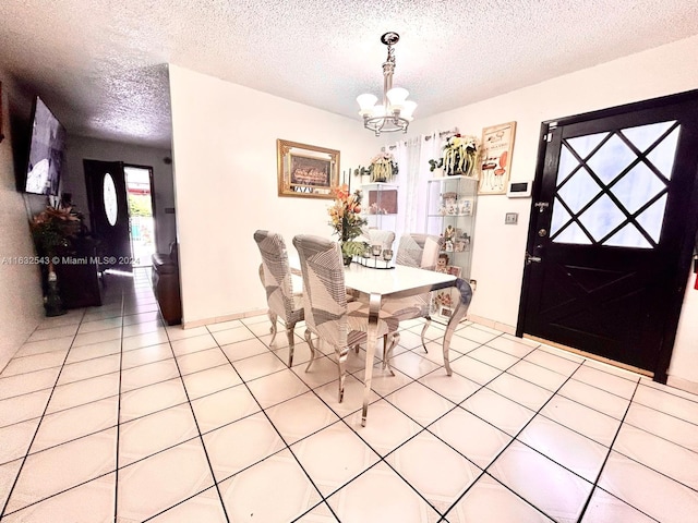 dining space with a textured ceiling, tile patterned flooring, and a notable chandelier