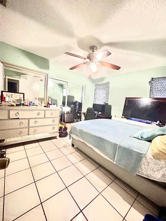 bedroom with ceiling fan, light tile patterned floors, and a textured ceiling