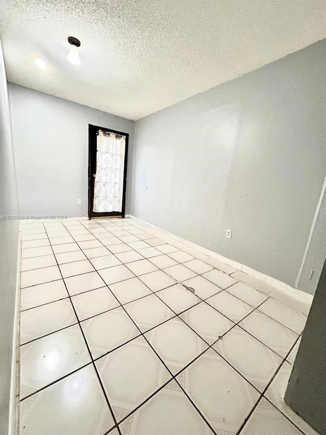 unfurnished room with a textured ceiling and light tile patterned floors