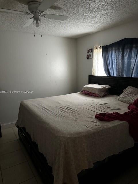 bedroom with a textured ceiling, ceiling fan, and tile patterned flooring