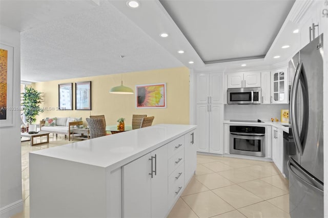 kitchen featuring white cabinetry, decorative light fixtures, light tile patterned floors, appliances with stainless steel finishes, and a raised ceiling