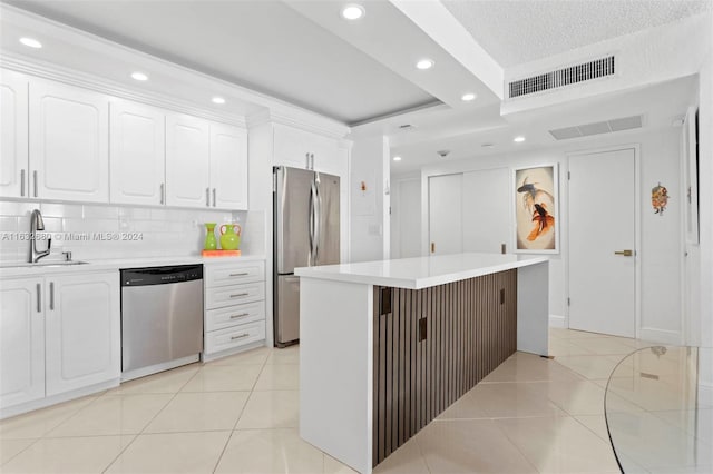 kitchen with sink, light tile patterned floors, appliances with stainless steel finishes, tasteful backsplash, and white cabinets