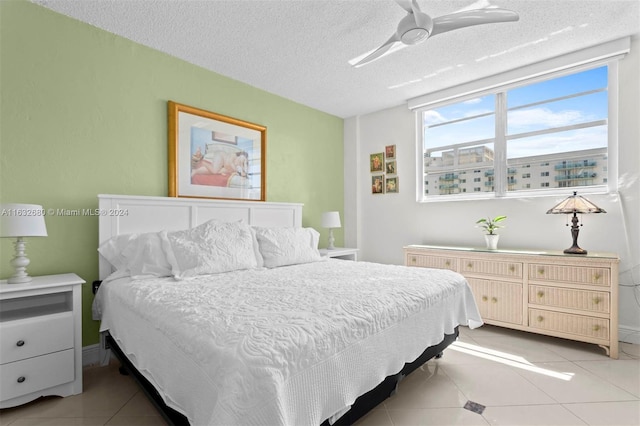 bedroom with ceiling fan, a textured ceiling, and light tile patterned floors