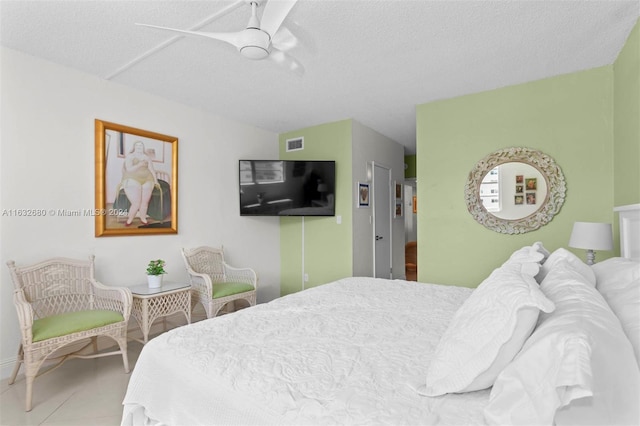 bedroom with ceiling fan, tile patterned flooring, and a textured ceiling