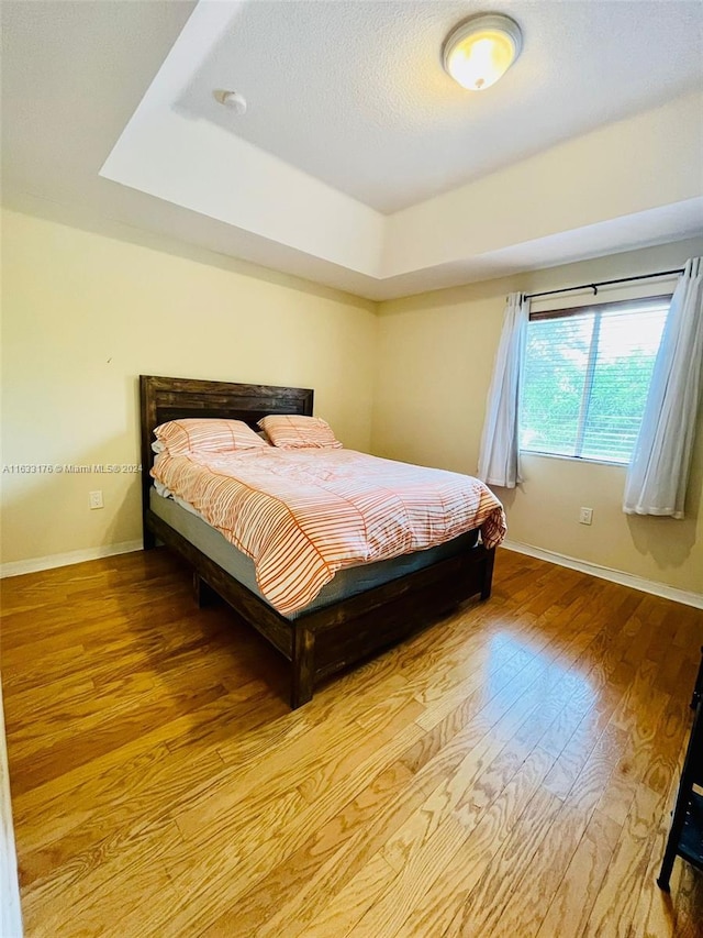 bedroom featuring light wood-type flooring and a tray ceiling