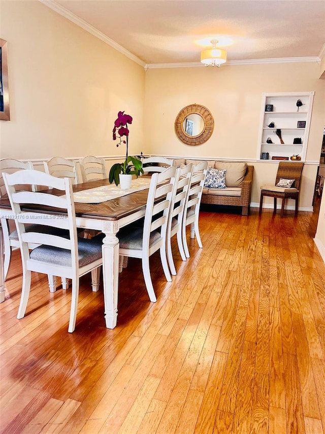 dining space featuring built in features, hardwood / wood-style floors, and crown molding