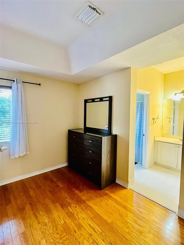 unfurnished bedroom featuring ensuite bath and hardwood / wood-style flooring