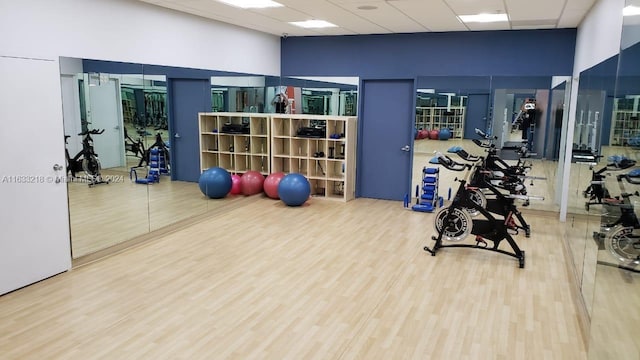 workout area with a high ceiling, a drop ceiling, and wood-type flooring