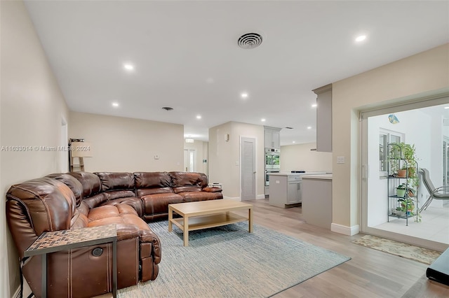 living area with light wood finished floors, visible vents, recessed lighting, and baseboards