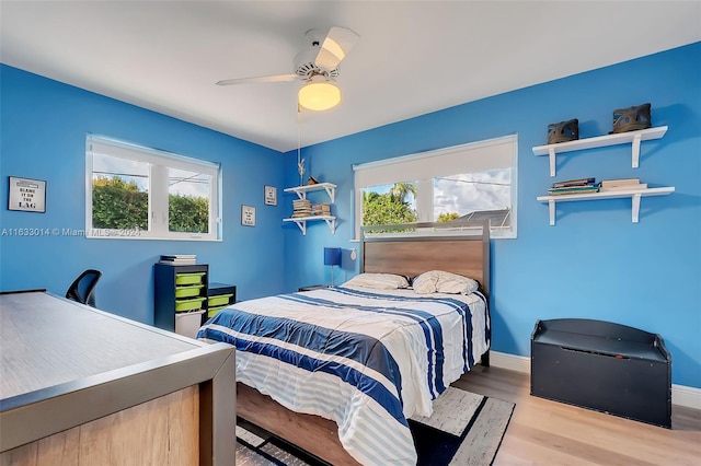 bedroom featuring multiple windows, ceiling fan, baseboards, and wood finished floors