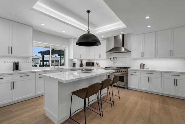 kitchen featuring appliances with stainless steel finishes, sink, wall chimney exhaust hood, and white cabinets