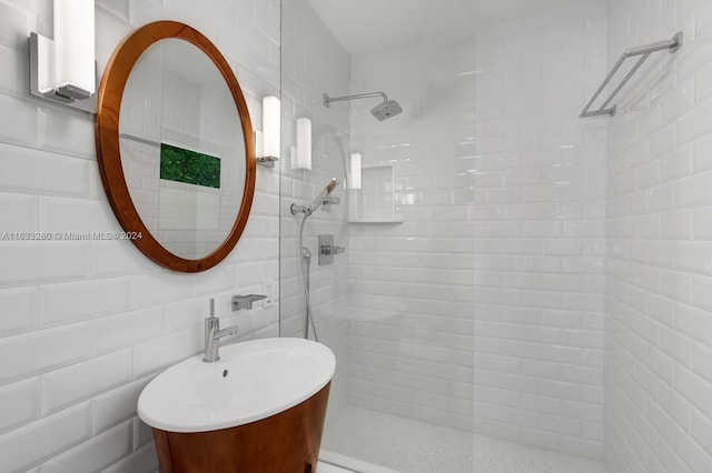 bathroom with sink, a tile shower, tile walls, and tasteful backsplash