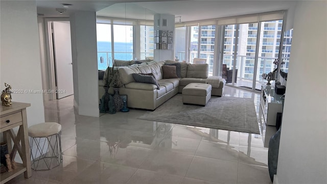 living room with a water view, floor to ceiling windows, and light tile patterned floors