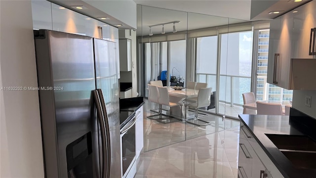 kitchen featuring stainless steel appliances, white cabinetry, expansive windows, and rail lighting