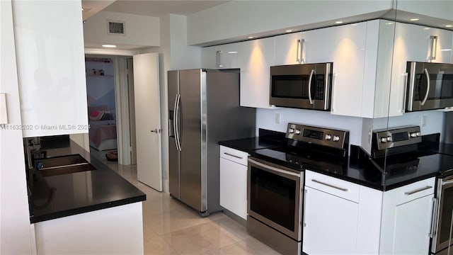 kitchen featuring stainless steel appliances, light tile patterned floors, and white cabinets