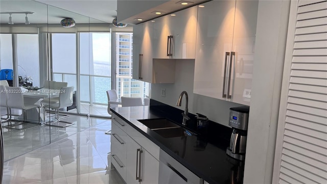 kitchen with white cabinetry, white dishwasher, and sink