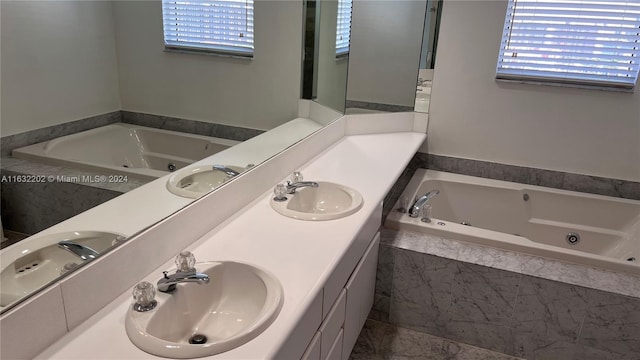 bathroom featuring vanity, tiled bath, and a healthy amount of sunlight