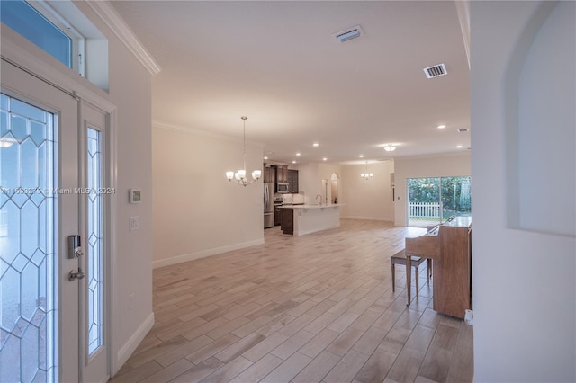 foyer entrance with light hardwood / wood-style floors, crown molding, and a chandelier