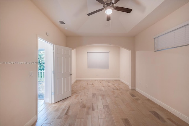 unfurnished room featuring a tray ceiling, ceiling fan, and light hardwood / wood-style floors