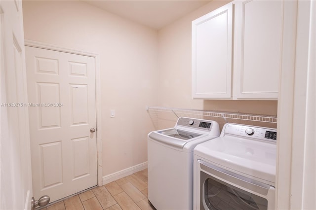 clothes washing area with light hardwood / wood-style floors, cabinets, and separate washer and dryer