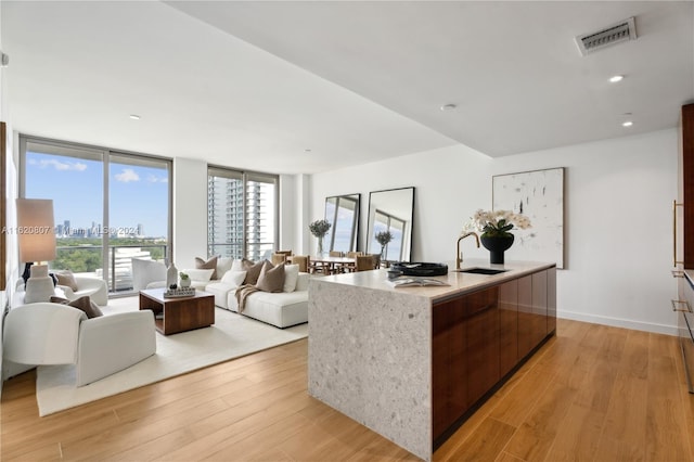 kitchen featuring light hardwood / wood-style flooring, a center island with sink, sink, and floor to ceiling windows