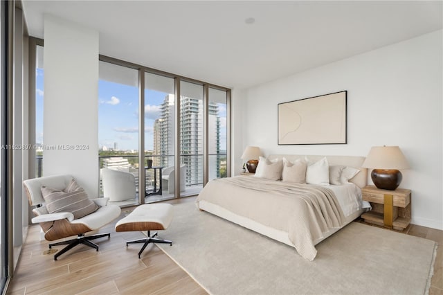 bedroom featuring light hardwood / wood-style floors, a wall of windows, and access to outside