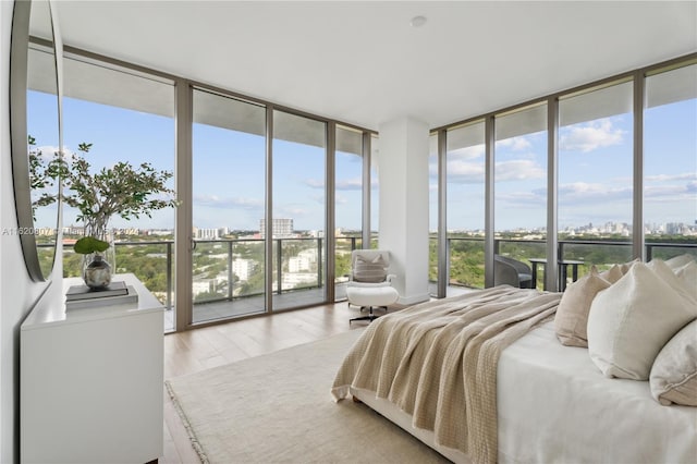 bedroom with multiple windows, light wood-type flooring, and floor to ceiling windows