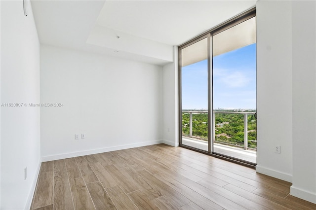 unfurnished room with a wall of windows and light hardwood / wood-style flooring