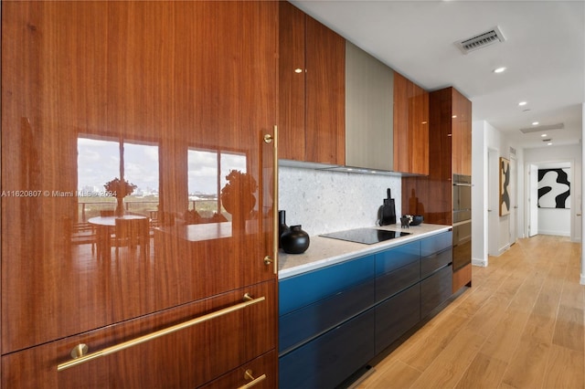 kitchen featuring light hardwood / wood-style flooring, black electric cooktop, and tasteful backsplash