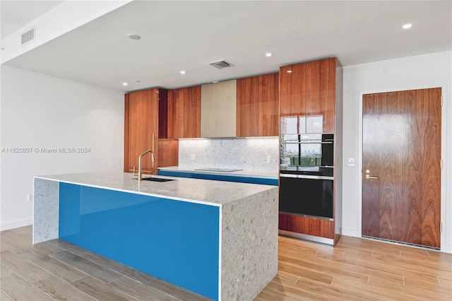 kitchen with sink, a center island with sink, and light hardwood / wood-style flooring