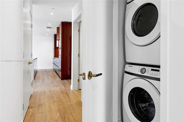 clothes washing area featuring stacked washer / dryer and light hardwood / wood-style floors