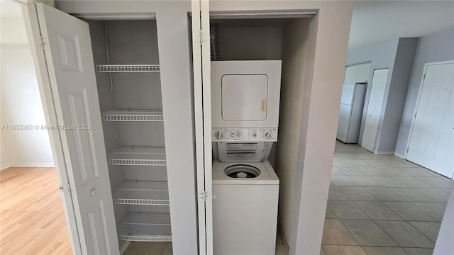 laundry area featuring stacked washer and dryer, laundry area, baseboards, and tile patterned floors