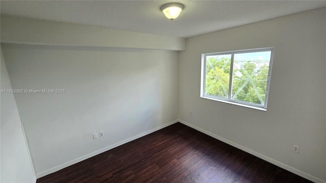 empty room featuring dark wood-type flooring and baseboards