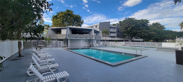 pool with a patio and fence