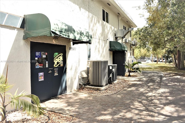 view of property exterior with central air condition unit and stucco siding