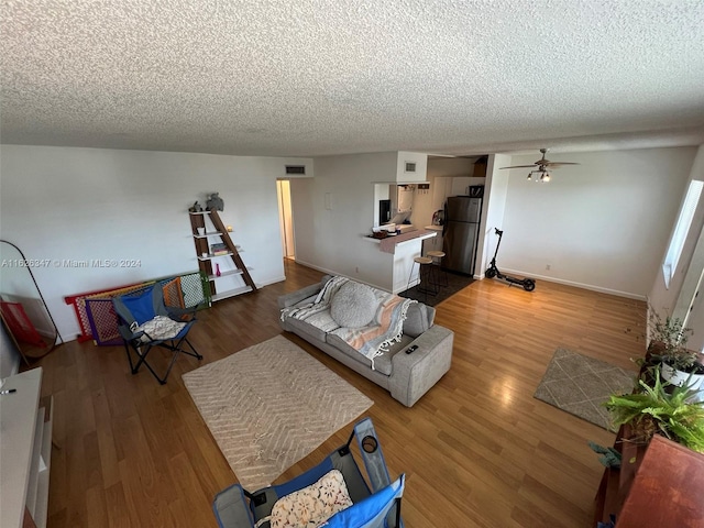 living room featuring a textured ceiling, hardwood / wood-style flooring, and ceiling fan