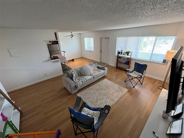 living room with ceiling fan, a textured ceiling, and light hardwood / wood-style flooring