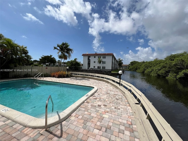 view of swimming pool with a patio area and a water view