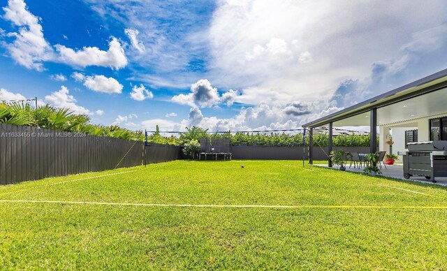 view of yard with a trampoline and a patio