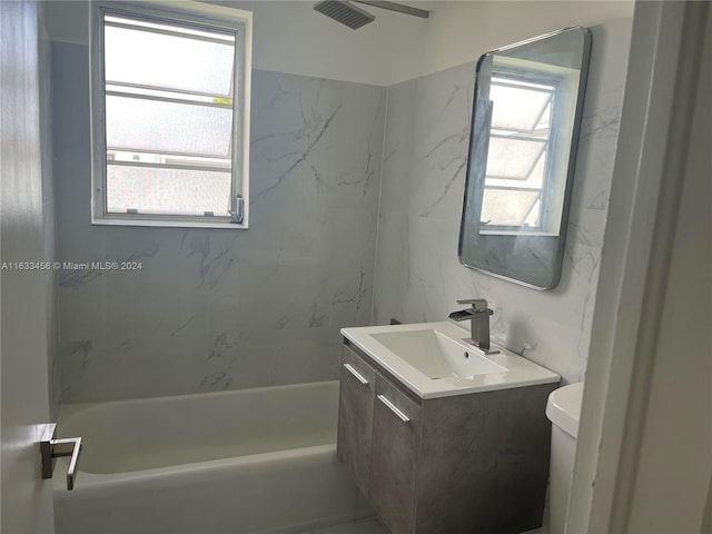 full bathroom featuring tiled shower / bath combo, vanity, and toilet