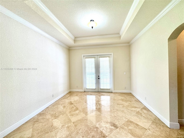 spare room featuring french doors, a textured ceiling, a tray ceiling, and crown molding