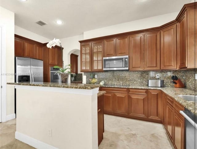 kitchen with backsplash, light tile patterned floors, stainless steel appliances, and light stone counters