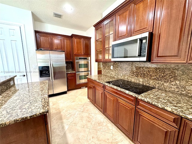 kitchen with stainless steel appliances, a textured ceiling, and stone counters