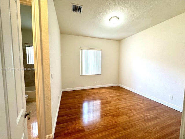 empty room featuring wood-type flooring and a textured ceiling