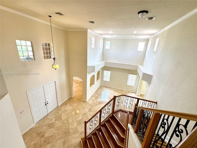 stairway featuring a textured ceiling and crown molding