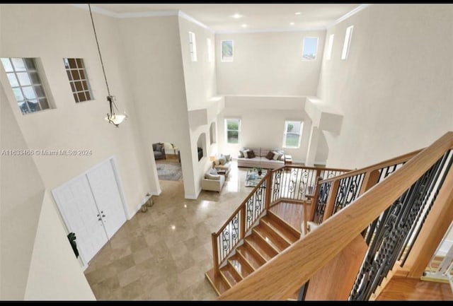 stairway with ornamental molding and a towering ceiling