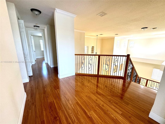 corridor featuring a textured ceiling, dark hardwood / wood-style floors, and ornamental molding