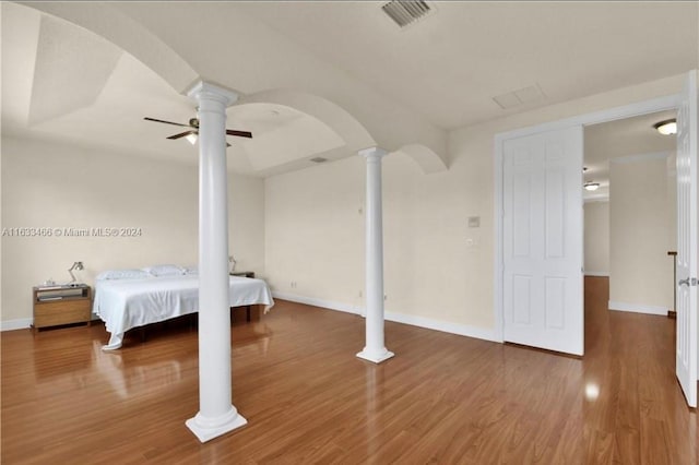 unfurnished bedroom with wood-type flooring, decorative columns, and ceiling fan