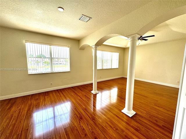 interior space with wood-type flooring, a textured ceiling, ceiling fan, and ornate columns